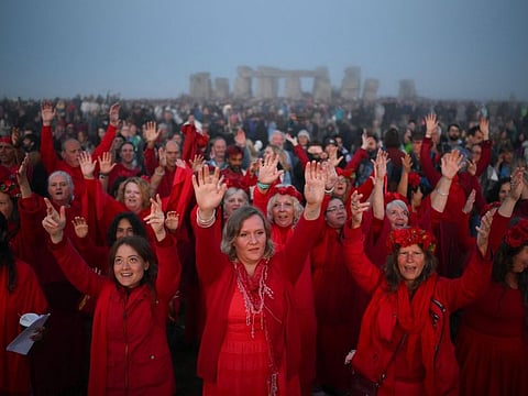 Revellers sing as they stand by the stones and wait for the sun to rise at Stonehenge, near Amesbury, in Wiltshire, southern England on June 21, 2023, to celebrate the celebrate the Summer Solstice festival, which dates back thousands of years, celebrating the longest day of the year when the sun is at its maximum elevation.