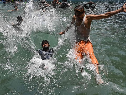 Youths cool themselves in a swimming pool on a hot summer day in Lahore on June 22, 2023.