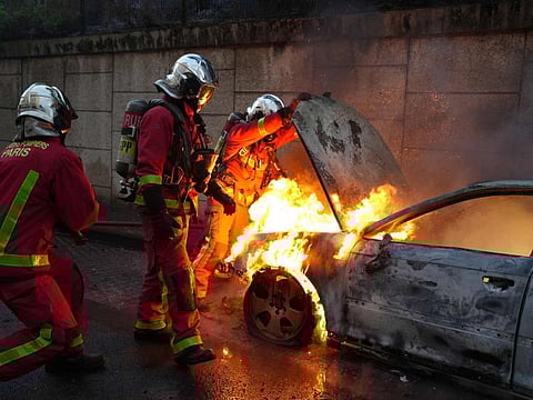 Firefighters extinguish a burning vehicle destroyed by protesters in Nanterre, west of Paris, on June 27, 2023, after French police killed a teenager who refused to stop for a traffic check in the city.