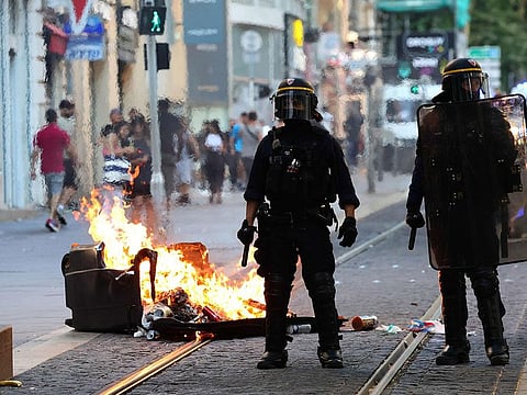 French riot police officers stand guard next to a burnt out trash bin during a demonstration against police in Marseille, southern France on July 1, 2023.