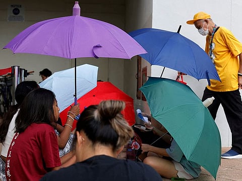 Maria Alia, 15, and her friends seek shade from the sun under umbrellas as they queue for Taylor Swift concert tickets in Singapore July 7, 2023.