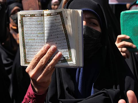 A demonstrator holds up a copy of the Quran, during a protest of the burning of a Quran in Sweden, in front of the Swedish Embassy in Tehran.