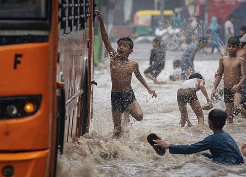Children play on a flooded road after heavy rains in New Delhi, on July 8, 2023.