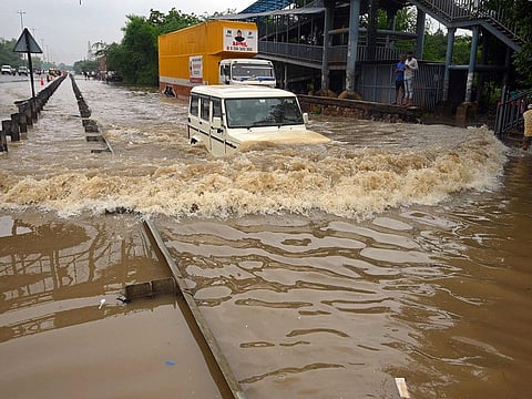 A commuter drives his car along a flooded highway after heavy monsoon rains in Gurgaon on the outskirts of New Delhi