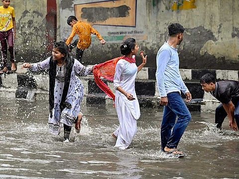 Youngsters play on waterlogged roads after heavy rainfall, in New Delhi on Monday, July 10, 2023.