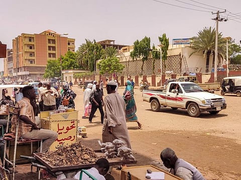 Pedestrians and vehicles move along a road outside a branch of the Central Bank of Sudan in the country's eastern city of Gedaref on July 9, 2023.