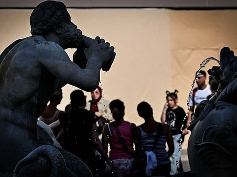 People stand next to a fountain at Piazza Navona in central Rome, on July 14, 2023, as Italy is hit by a heatwave.