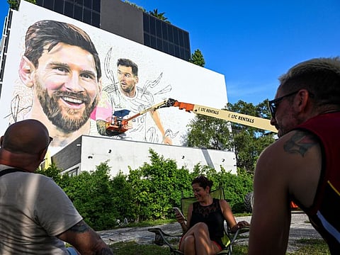 People watch as Argentine artist Maximiliano Bagnasco paints a mural of Lionel Messi in Wynwood, Miamis art district, in Miami, Florida on July 10.