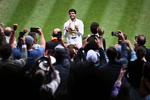Spain's Carlos Alcaraz holds the winner's trophy as he smiles to the stands at The All England Tennis Club in Wimbledon, southwest London, on Sunday.