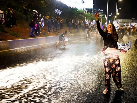 Protesters being sprayed by a water canyon during a demonstration against Israeli Prime Minister Benjamin Netanyahu and his nationalist coalition government's plan for judicial overhaul, in Tel Aviv.
