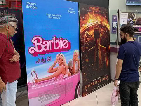 Moviegoers look at posters of 'Barbie' and 'Oppenheimer' at a cineplex on July 21, 2023.