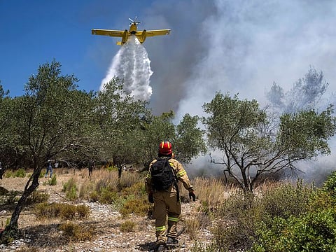 An aircraft drops water over a wildfire in Vati village, on the Aegean Sea island of Rhodes, southeastern Greece.