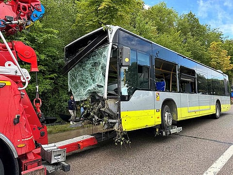 A damaged bus being towed away after an accident during which it drove off the road attempting to avoid a collision with a vehicle driving the wrong way