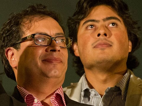 Gustavo Petro, left, waves to supporters as his son Nicolas looks on, January 13, 2014.