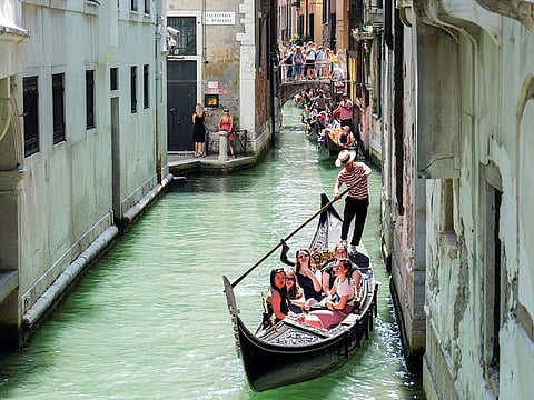 Gondoliers row their gondolas through the Venice Canal.