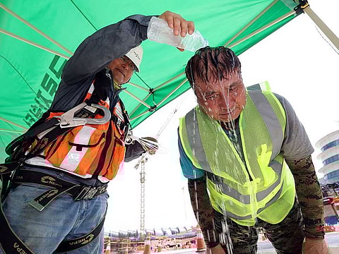 A worker pours cold water in a plastic bottle on his colleague in order to cool off him at a construction site in Incheon, South Korea.