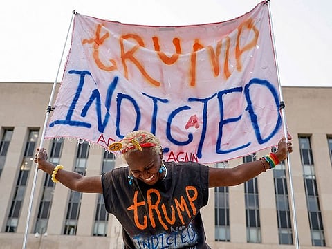 A woman holds a banner in front of the federal courthouse where former US President and Republican presidential candidate Donald Trump is expected later this week to answer charges after a grand jury returned an indictment of Trump in the special counsel's investigation of efforts to overturn his 2020 election defeat in Washington, on August 1, 2023.