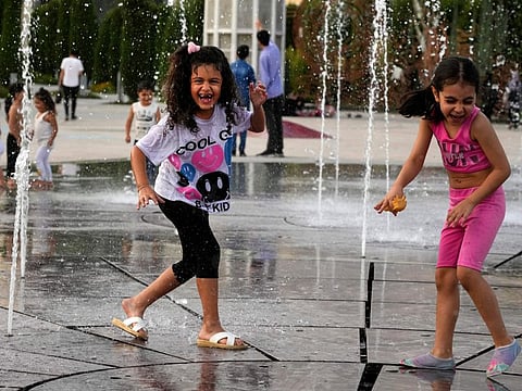 Children enjoy a water fountain at the Ebrahim Park while temperature reaches 38 C (100.4 F) in Tehran on August 2, 2023.