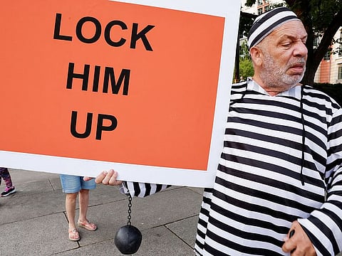 A man holds a sign in front of the E. Barrett Prettyman Federal Courthouse ahead of Donald Trump's arraignment in Washington, on August 2, 2023.