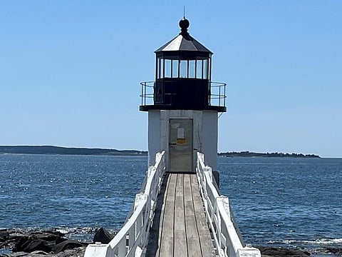 The Marshall Point lighthouse sits on the water's edge with its damaged light removed.