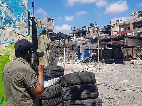 File photo: A member of Palestinian President Mahmoud Abbas' Fatah group stands guard in front of houses riddled with bullets after the deadly clashes between factions in the refugee camp of Ein Al Hilweh near the southern port city of Sidon, Lebanon, Thursday, Aug. 3, 2023.