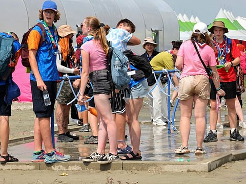 Attendees of the World Scout Jamboree cool off with water at a scout camping site in Buan, South Korea, Friday, Aug. 4, 2023. More than 100 people were treated for heat-related illnesses at the World Scout Jamboree being held in South Korea, which is having one of its hottest summers in years.