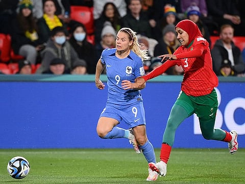 France's forward Eugenie Le Sommer runs with the ball followed by Morocco's defender Nouhaila Benzina during the match between France and Morocco.