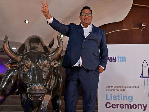 Paytm founder and CEO Vijay Shekhar Sharma gestures as he poses with a bronze replica of the Charging Bull of Wall Street, after the company's IPO listing ceremony at the Bombay Stock Exchange (BSE) in Mumbai, India, November 18, 2021.