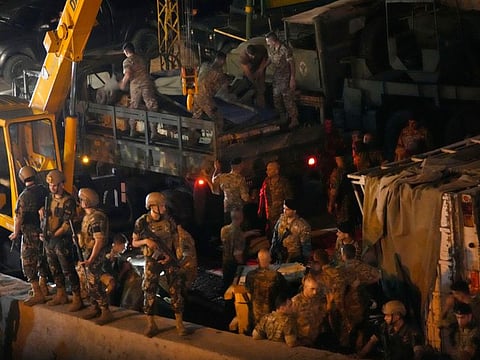 Lebanese soldiers, top left, standing on their military truck cover boxes that were moved from an overturned truck, right, in the Christian town of Kahaleh, Lebanon on August 9, 2023.