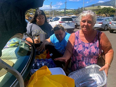 Vilma Reed, 63, her daughter Amanda Hernandez, 45, and grandson Natanael Hernandez, 18, stand next to their car with donations for those affected by a wildfire