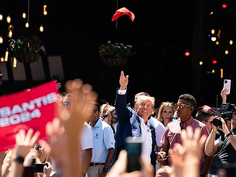 Former president Donald Trump tosses a hat in the air while supporters cheer for him on August 12, 2023, during the 2023 Iowa State Fair, in Des Moines.