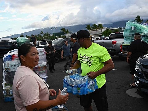 Volunteers load pallets of supplies and aid donations flown in from the Hawaiian island of Kauai into pickup trucks at the Kahului airport cargo terminal in the aftermath Maui wildfires in Kahului, Hawaii on August 13, 2023.