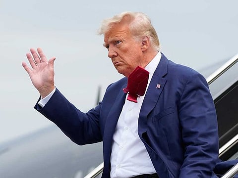 Former President Donald Trump waves as he steps off his plane at Ronald Reagan Washington National Airport, Aug. 3, 2023, in Arlington, Va.