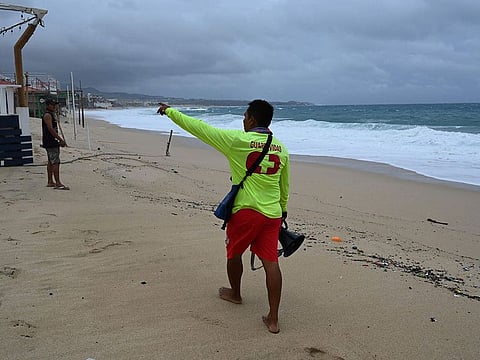 Local government lifeguard Julio Cesar Tehuitzin asks a young man to leave the beach in Los Cabos, Baja California State, Mexico, during the passage of Hurricane Hilary, on August 19, 2023.