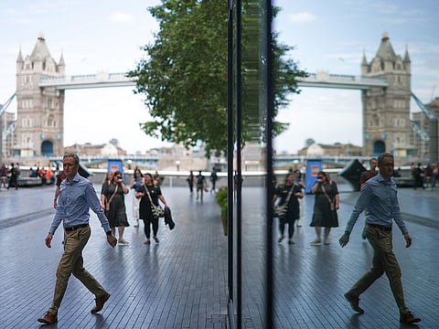 People reflected in a building glass, walk on the Southbank of the River Thames, with London Bridge on the background, central London.
