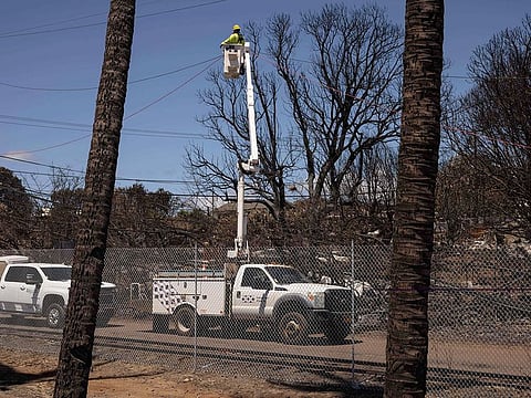 A Hawaiian Electric employee repairs power lines in the aftermath of the Maui Fires in Lahaina, West Maui, Hawaii.
