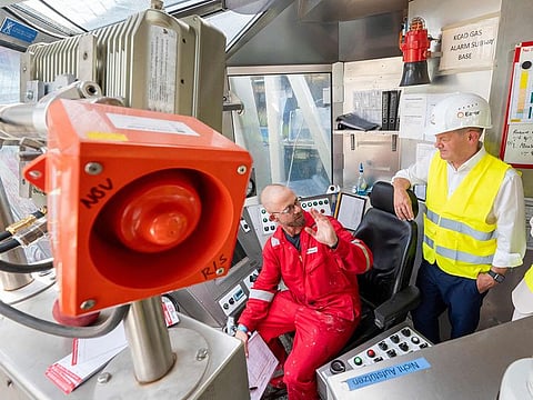 German Chancellor Olaf Scholz (R) talks with an employee of Eavor New Technologies on a drilling tower during his visit of a "green energy" geothermal power station in Geretsried, southern Germany, on August 24, 2023.