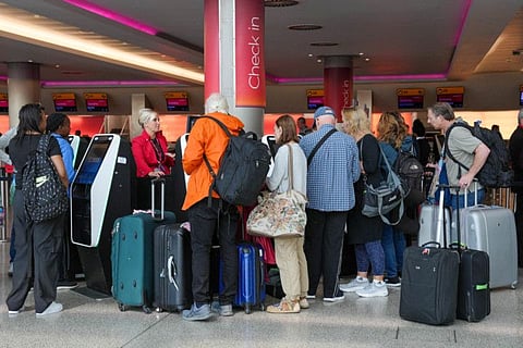 Passengers queue for the assistance with self check-in machines at Heathrow Terminal 3 in London.