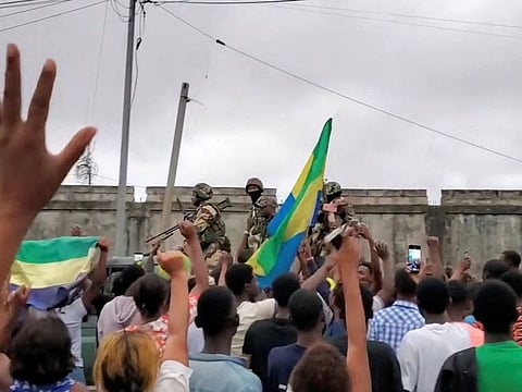 A military vehicle passes by people after military officers announced they had taken power, after the state election body announced President Ali Bongo had won a third term, in Port Gentil, Gabon