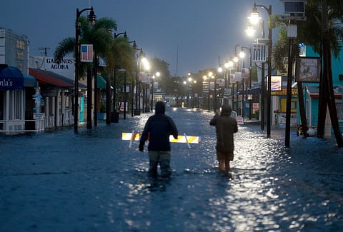 Reporters wade through flood waters as it inundates the downtown area after Hurricane Idalia passed offshore on August 30, 2023 in Tarpon Springs, Florida.