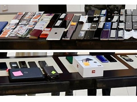 Cash, smartphones, digital tablets, banks cards, notes and other items siezed by UAE police from the suspected electronic fraudsters.