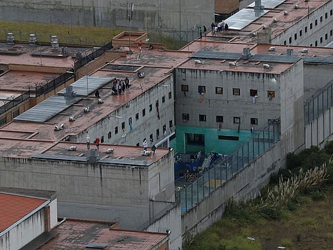 Prisoners stand on the roof of the Turi jail where dozens of prison guards and police officers have been kidnapped by the inmates, in Cuenca, Ecuador, Thursday, Aug.31, 2023.