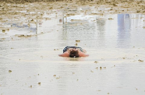 A Burning Man attendee lies in the mud at the event in Black Rock City, in the Nevada desert, after a rainstorm turned the site into mud on September 2, 2023.