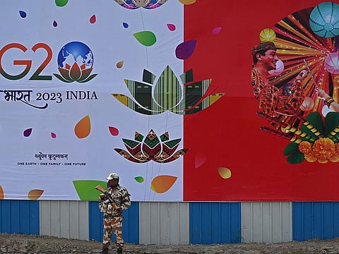 A security personnel stands guard in front of a G20 India summit hoarding along a street in New Delhi on September 5, 2023, ahead of its commencement.