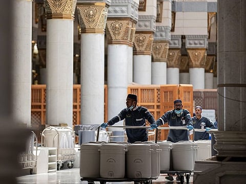 Workers at the Prophet’s Mosque in Medina serve Zamzam water containers to worshippers.
