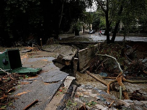 People walk near a collapsed road after torrential rains destroyed the infrastructure and caused flooding in the area in the village of Ano Meria, near Volos, central Greece.