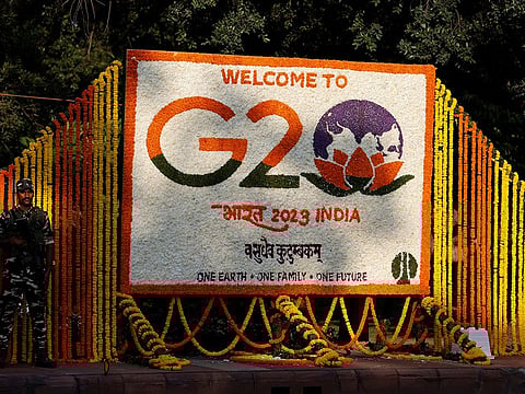 A security force personnel stands guard next to a hoarding decorated with flowers on a pavement ahead of the G20 Summit in New Delhi, India, September 8, 2023.