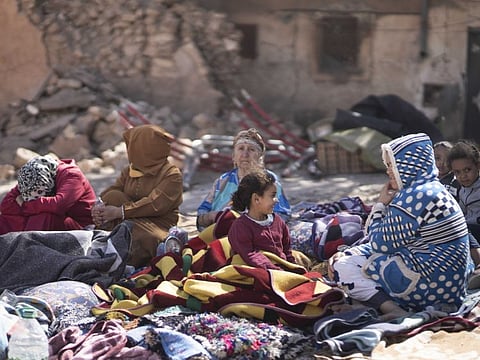 Families sit outside their destroyed homes after an earthquake in Moulay Brahim village, near Marrakesh.
