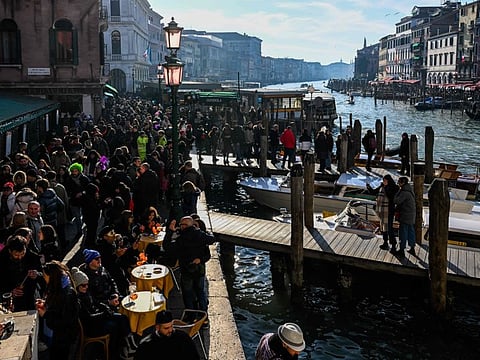 Visitors and tourists gather by the Grand Canal during the Venice carnival on February 11, 2023.