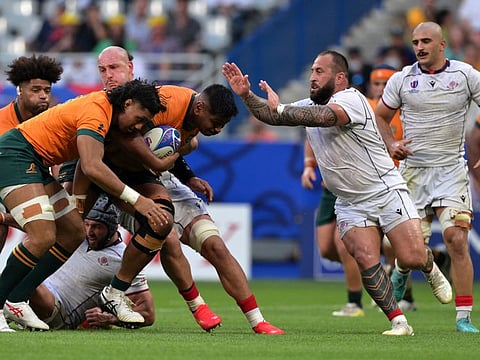 Australia's lock and captain Will Skelton (centre) runs with the ball as Georgia's prop Beka Gigashvili (right) goes to block him during the France 2023 Rugby World Cup Pool C match.